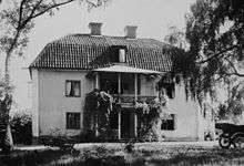 Two-storey, light-coloured building with a gambrel roof