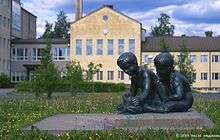 Bronze sculpture of a young boy and girl kneeling to examine a frog