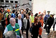 Woman walking through a disaster area with many other people