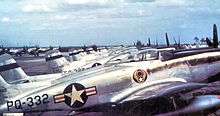 A lineup of silver piston-engined fighters, the one in the front of the line with clearly visible U.S. Air Force insignia and 'PQ-332" coding on the rear fuselage