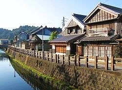 A small street and wooden houses next to a canal.