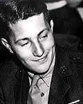 Head of a young man in a military jacket and tie, looking down and to the right