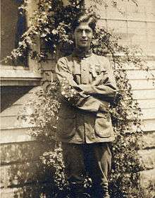 Young man in an 1910 era Boy Scout uniform displaying the merit badges on his sleeve