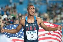 Eaton Ashton in a running vest holding the American flag behind him.