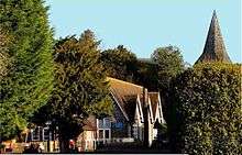 A front-facing view of Bentworth's Primary School with the church spire directly behind