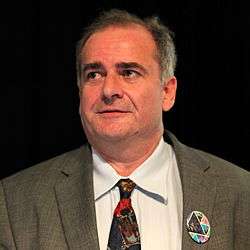 Caspar Bowden on black background, giving a speech