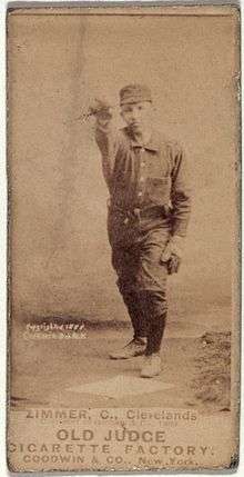 A sepia-toned baseball card image of a man wearing a dark-colored old-style baseball uniform and cap with his right arm raised in the air