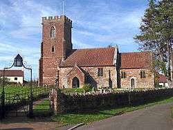 Reddish stone building with square tower.