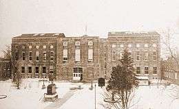 A sepia-toned photograph of a large, rectangular building.