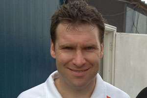 A headshot of a Caucasian man with brown hair in a white polo shirt.