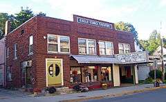 A two-story brick building with a rectangular facade and flat roof. A sign in the middle of the top of the building says "Galli-Curci Theatre". The ground floor has a storefront with dressed mannequins and a triangular marquee saying "Coming Soon: A Movie Theatre Near You" on the right.