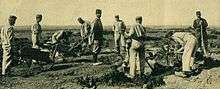 A party of German prisoners works the ground with picks under the supervision of a French guards