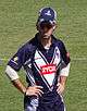 An Australian cricketer wearing blue-white jersey and a cap.