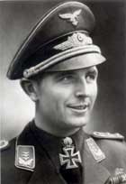 The head of a young man, shown from the front. He wears a military uniform and a white shirt. His hair appears dark and his facial expression is a determined and smiling; his eyes are looking to the right of the camera.