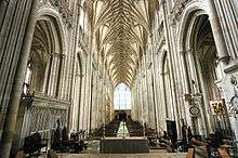 This interior view at Winchester shows the whole length of the nave, which has huge stone piers that appear to comprise clusters of upward-sweeping stone shafts. The stone vault has ribs which sweep up to a point like the branches of trees in a forest. The overall effect is visually spectacular.