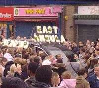 Car decorated with flowers, surrounded by a large crowd