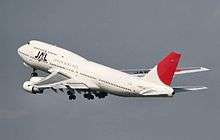 Side quarter view of four-engine jet climbing in the sky.