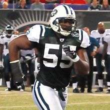 African american male wearing white helmet and green uniform with "55" shown on the front