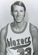 A smiling man wears a Portland Trail Blazers jersey.