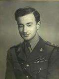 male in uniform tunic, collar and tie no headress on his leftbreast can be seem medal ribbons and SAS pattern parachute wings. He is also wearing a Sam Browne belt