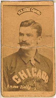 A baseball player is shown sitting, facing slightly left of the camera.