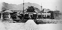 The front entrance of a fort with mountains in the background.