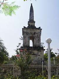 Tall stome memorial with spire and surrounded by a metal fence.