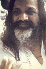 Closeup portrait of an Indian man with long black hair and mustache, and white beard