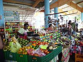 Vendor selling numerous types of fruit, vegetables and beverages.