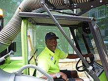 Waist high portrait of man in his thirties driving a sidewalk cleaning machine