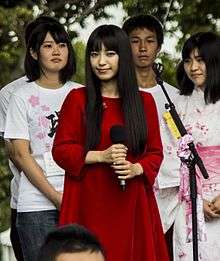 A woman in a red dress surrounded by Japanese students.