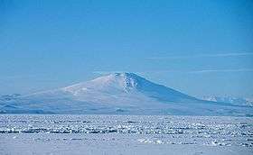  Distant view over an ice-covered sea of a conical mountain