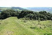 A low green ridge bends away to the right, in the background is a distant shore below the hill