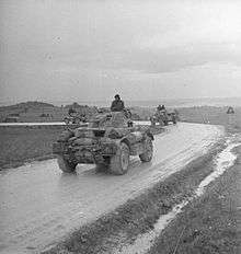 Three tank-like cars rounding a curve on a wet road