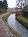 The Niemica River flowing next to a path and under a bridge in Golczewo.