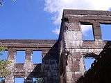 Ruined stone wall showing blue sky through window holes.