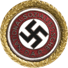 a circular golden badge with a central swastika