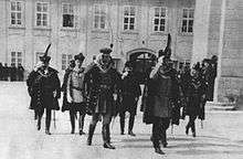 Group of people in formal garb, including swords