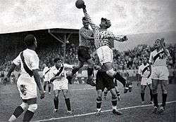 Photograph of a goalkeeper slapping a football out of his area