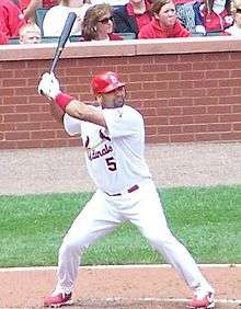 A man with feet spread apart holding a baseball bat in the air