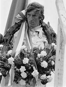 Photograph of Jochen Rindt on a winner's rostrum with a laurel wreath around his neck