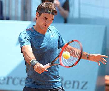 A tennis player holds a racket in his hand