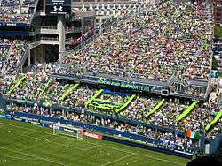 Fans unfurling a green and blue tifo behind a goal.