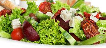 Assorted salad vegetables in a platter, against a white background