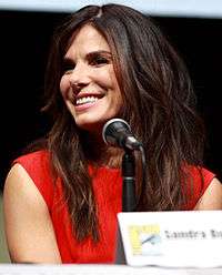 A picture of a brown hair lady wearing her hair down. She wears a red dress.