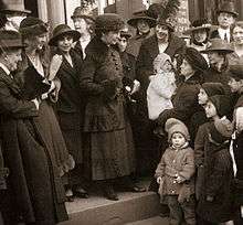 A well-dressed woman stands on courthouse steps, surrounded by a crowd of supporters.