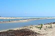 A river flows out to sea between stone jetties