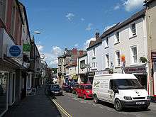 Street scene with cars on a road with buildings on either side.