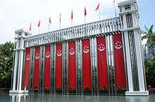 Different types of flags and banners being flown at a structure in Istana Park.