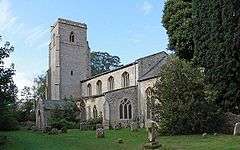 A stone church seen from the southeast with a chancel, nave with clerestory, south aisle and porch and a tower